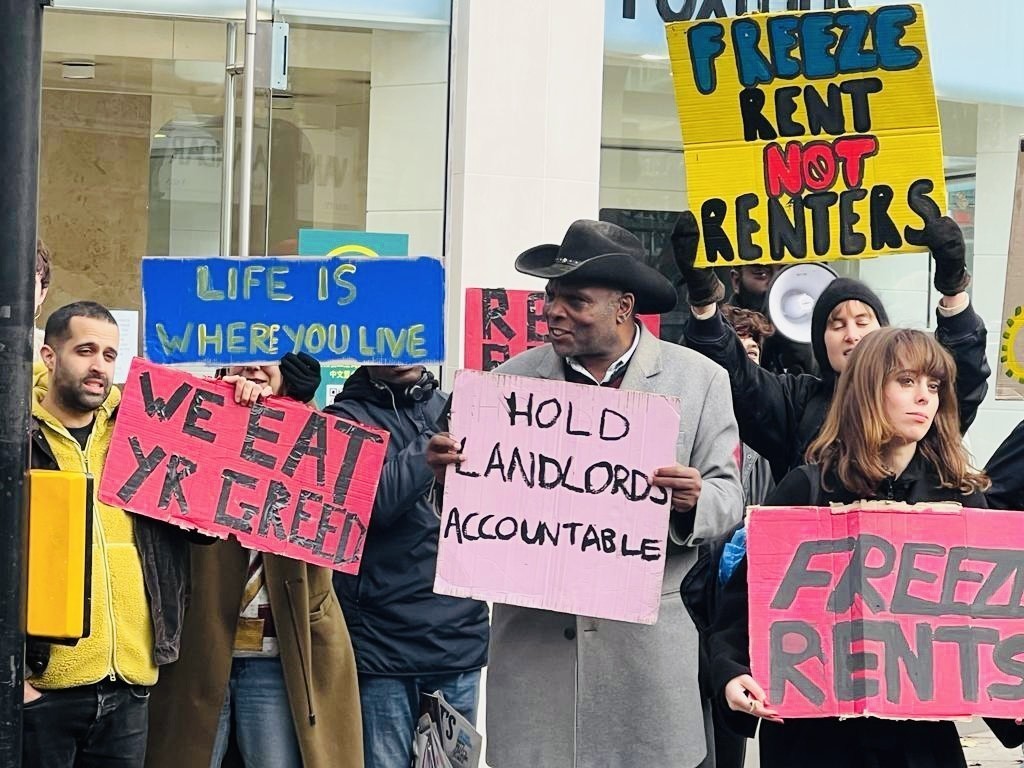 Image shows a group of protesters holding signs including 'Life is where you live', 'Hold ladnlords accountable' and 'Freeze rents not renters'.